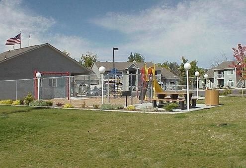 a yard with a playground and houses in the background